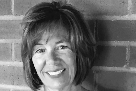 White woman in short hair standing in front of brick wall